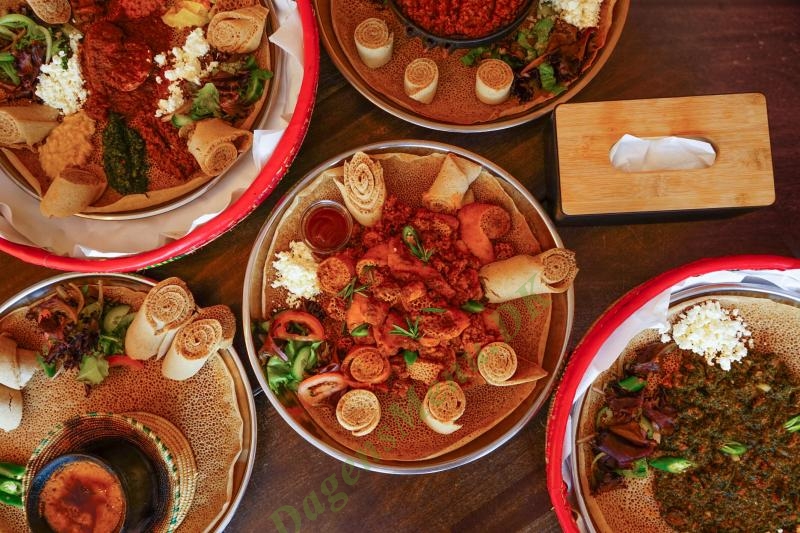 A table at Hidmona covered with shared platters of Eritrean dishes on injera